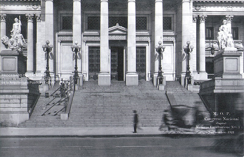 Explanada del Congreso. Carro pasa difuso. Hombres trabajando. Puerta abierta. Esculturas de Lola Mora.