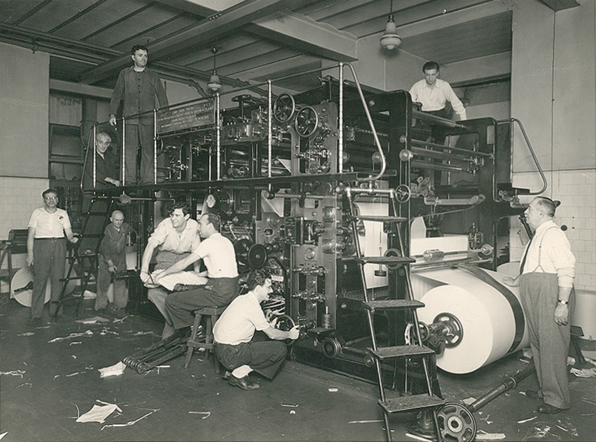 Hombres trabajando en la máquina para imprimir. Señor mayor apoyando su mano sobre la bobina de papel