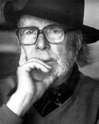 Fotografía del artista en blanco y negro con sombrero y anteojos