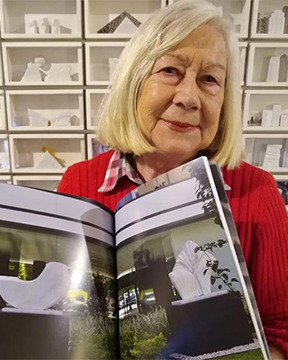 Fotografía de la artista mostrando un libro con su obra