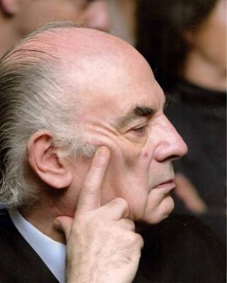 Fotografía del artista en color, mirando de costado, con la mano apoyada en la cara